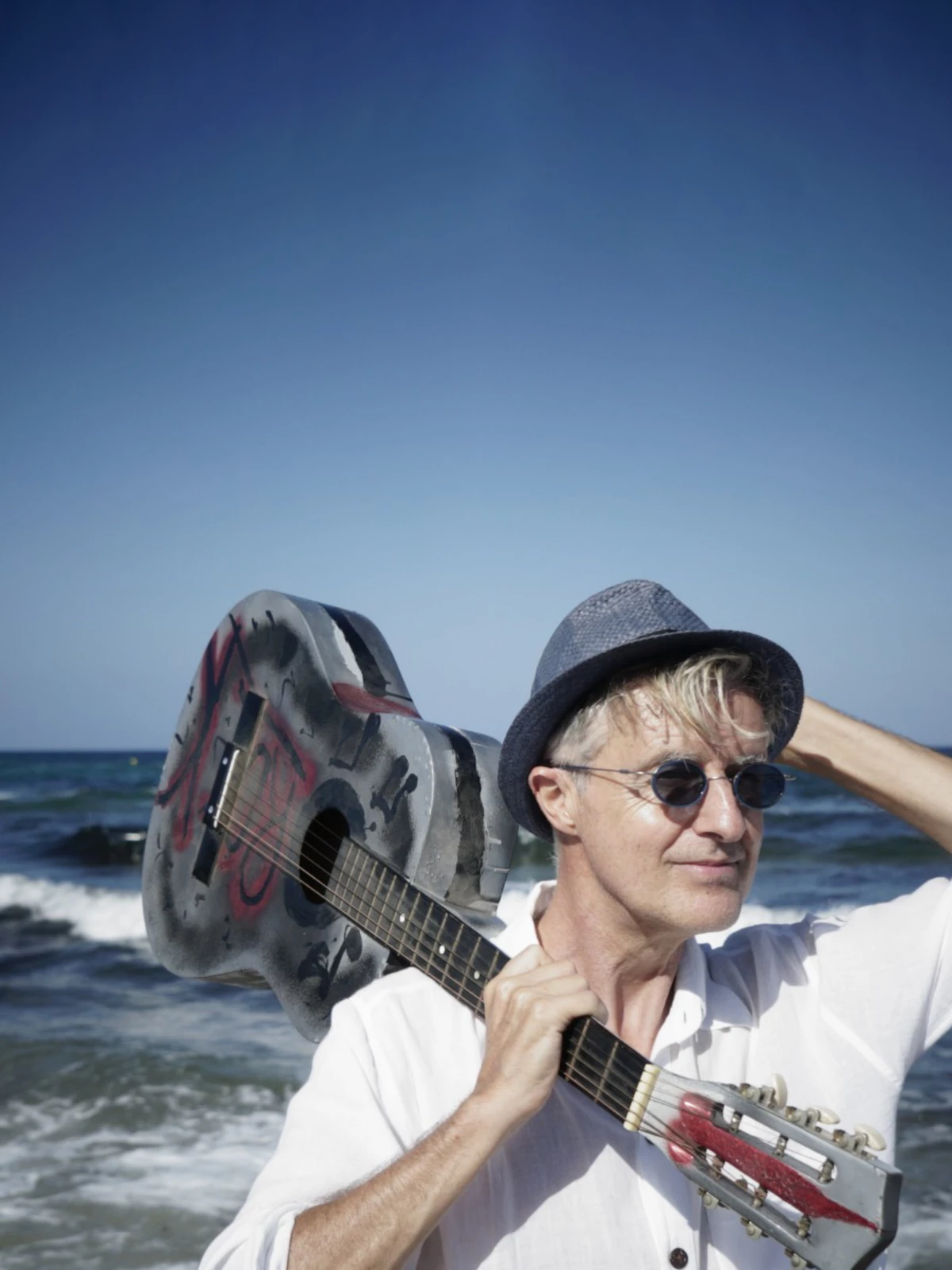 Chris Le Blanc with guitar over his shoulder on the beach