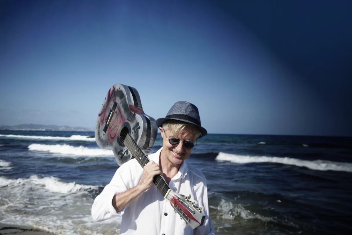 Chris Le Blanc on the beach with a guitar over his shoulder